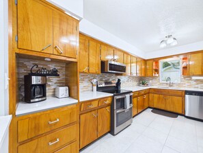 A modern kitchen with wooden cabinets, stainless steel appliances, and a tiled backsplash. - Whether you're bringing your boat, planning a family vacation, or simply looking for a peaceful coastal retreat, this home delivers an unforgettable Space Coast experience. (Cocoa Beach)