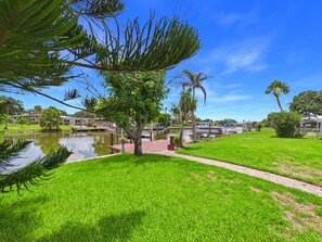 A park with a pond, pathways, and a variety of trees including a palm. - Whether you're bringing your boat, planning a family vacation, or simply looking for a peaceful coastal retreat, this home delivers an unforgettable Space Coast experience. (Cocoa Beach)
