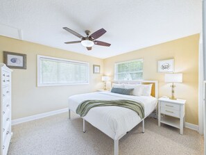 A bedroom with a bed, two bedside tables with lamps, a ceiling fan, and a window with blinds. - Whether you're bringing your boat, planning a family vacation, or simply looking for a peaceful coastal retreat, this home delivers an unforgettable Space Coast experience. (Cocoa Beach)