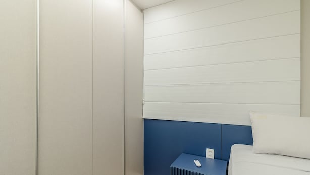 A modern hotel room with a bed, a small bedside table, and a wall with horizontal lines. - Ap w/ Amazing View and Pool the Building - Txp1101 (Goiânia)