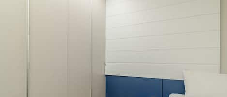 A modern hotel room with a bed, a small bedside table, and a wall with horizontal lines.
