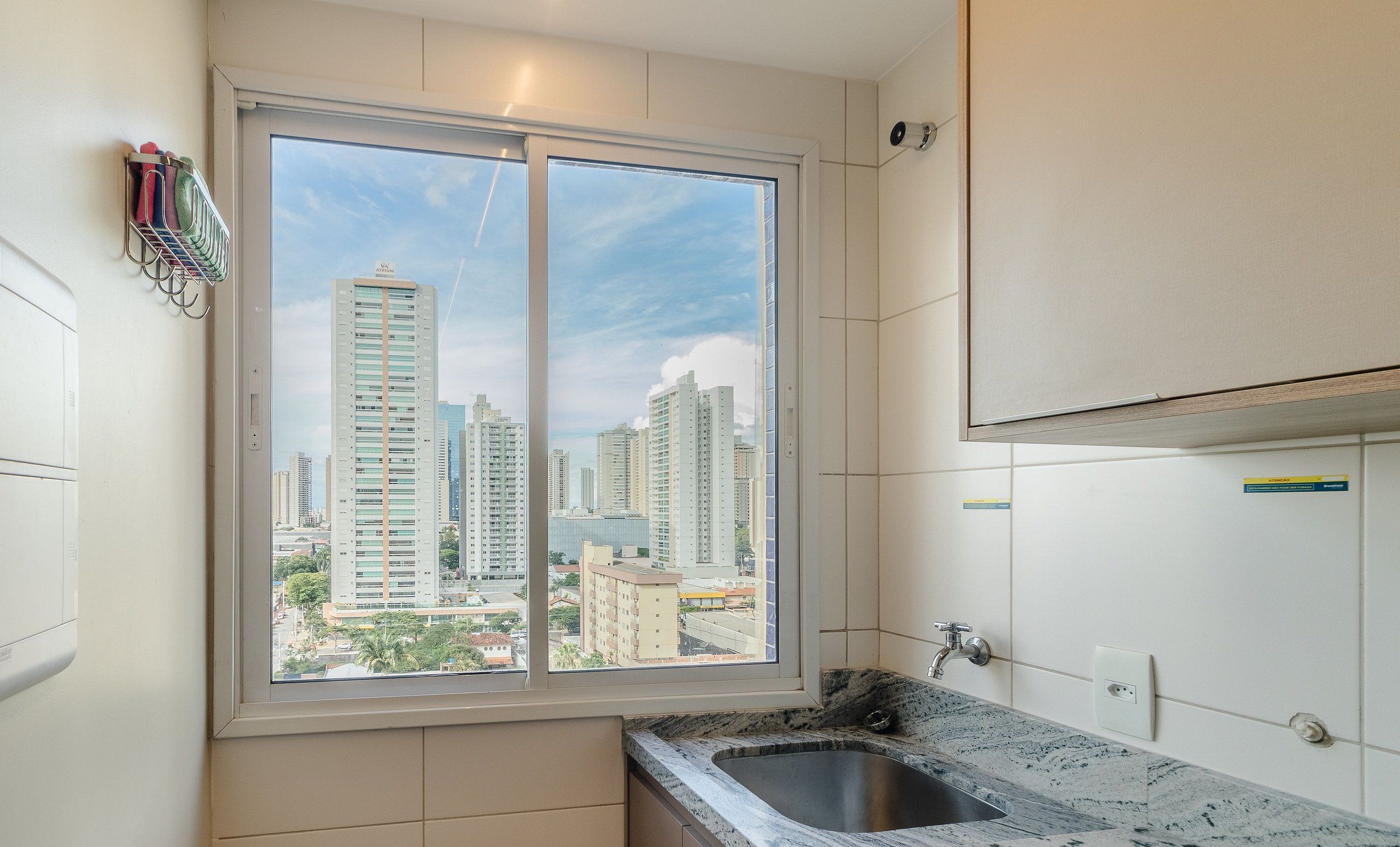A modern kitchen with a large window, a built-in sink, and a view of high-rise buildings.