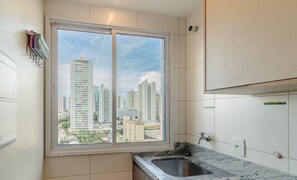 Una cuina moderna amb un gran finestral, un vàter integrat i vista a edificis alts.