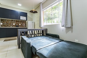 A small, modern room with a bed, a kitchenette, and a window with curtains. - Comfortable Studio Facing the Lagoon Sdr008 (Florianópolis)