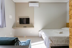 Une chambre d’hôtel avec un lit, un téléviseur fixé au mur, un canapé et un mur décoratif en bois.