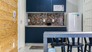 A compact kitchen with a microwave, a refrigerator, and a tiled backsplash. - Comfortable Studio Facing the Lagoon Sdr008 (Florianópolis)