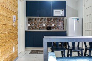 Une cuisine compacte équipée d’un four à micro-ondes, d’un réfrigérateur et d’un plan de travail carrelé.
