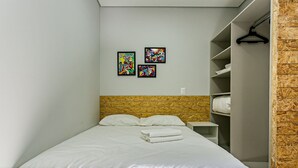A neatly made bed with white linens, a wooden headboard, and a wall with three colorful artworks. - Comfortable Studio Facing the Lagoon Sdr008 (Florianópolis)