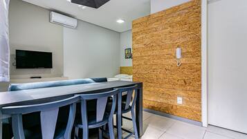 A modern dining area with a long table and chairs, a flat-screen TV, and a wooden accent wall.