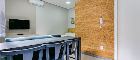 A modern dining area with a long table and chairs, a flat-screen TV, and a wooden accent wall.