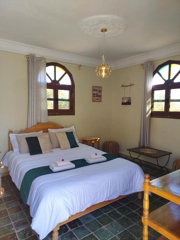 Un dormitorio con una cama, una mesa y un lámpara colgante.