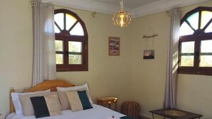 Un dormitorio con una cama, una mesa y un lámpara colgante.