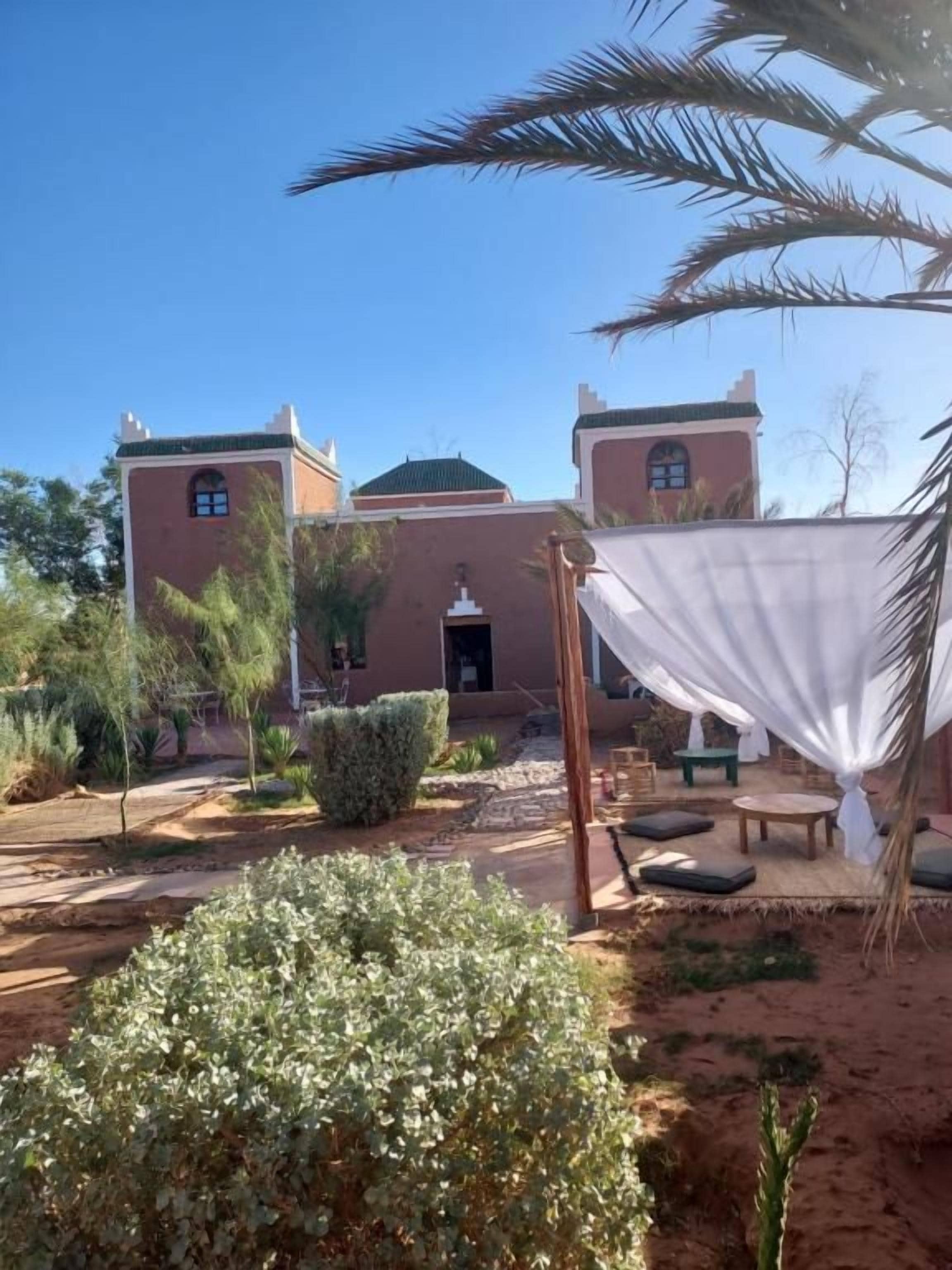 Un edificio de estilo arquitectónico tradicional, con un área de estar al aire libre cubierta y un jardín bien cuidado.