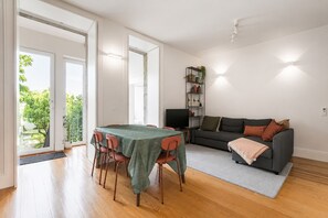 Moderni olohuone, jossa on ruokailutila, sohva, televisio ja kirjahylly.