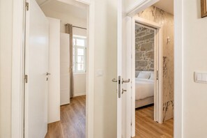 A hotel room with a bed, a stone wall, and a wooden floor. - Taipas House in Porto 2 (Porto)