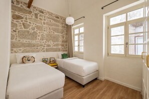 Un dormitorio con dos camas, una pared de piedra y una ventana con vistas.