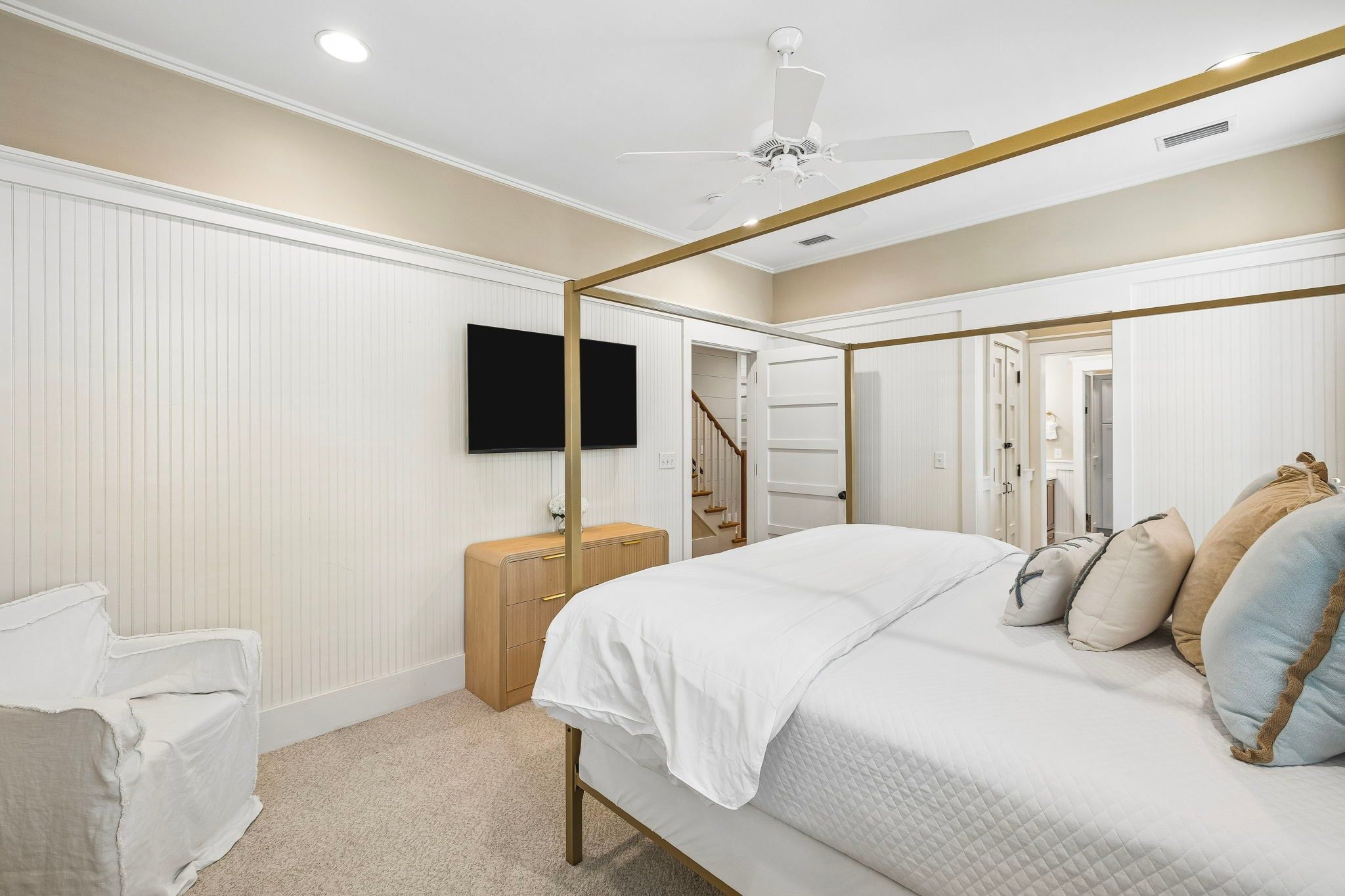 A bedroom with a four-poster bed, a television mounted on the wall, and a wooden nightstand.