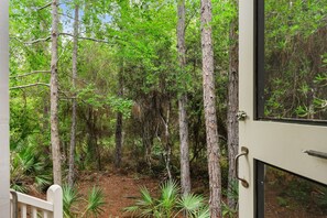 A view of a forested area with tall trees and a wooden deck. - EZ Walk to Camp WaterColor! LSV/Golf Cart & 4 Bikes Included! (Santa Rosa Beach)