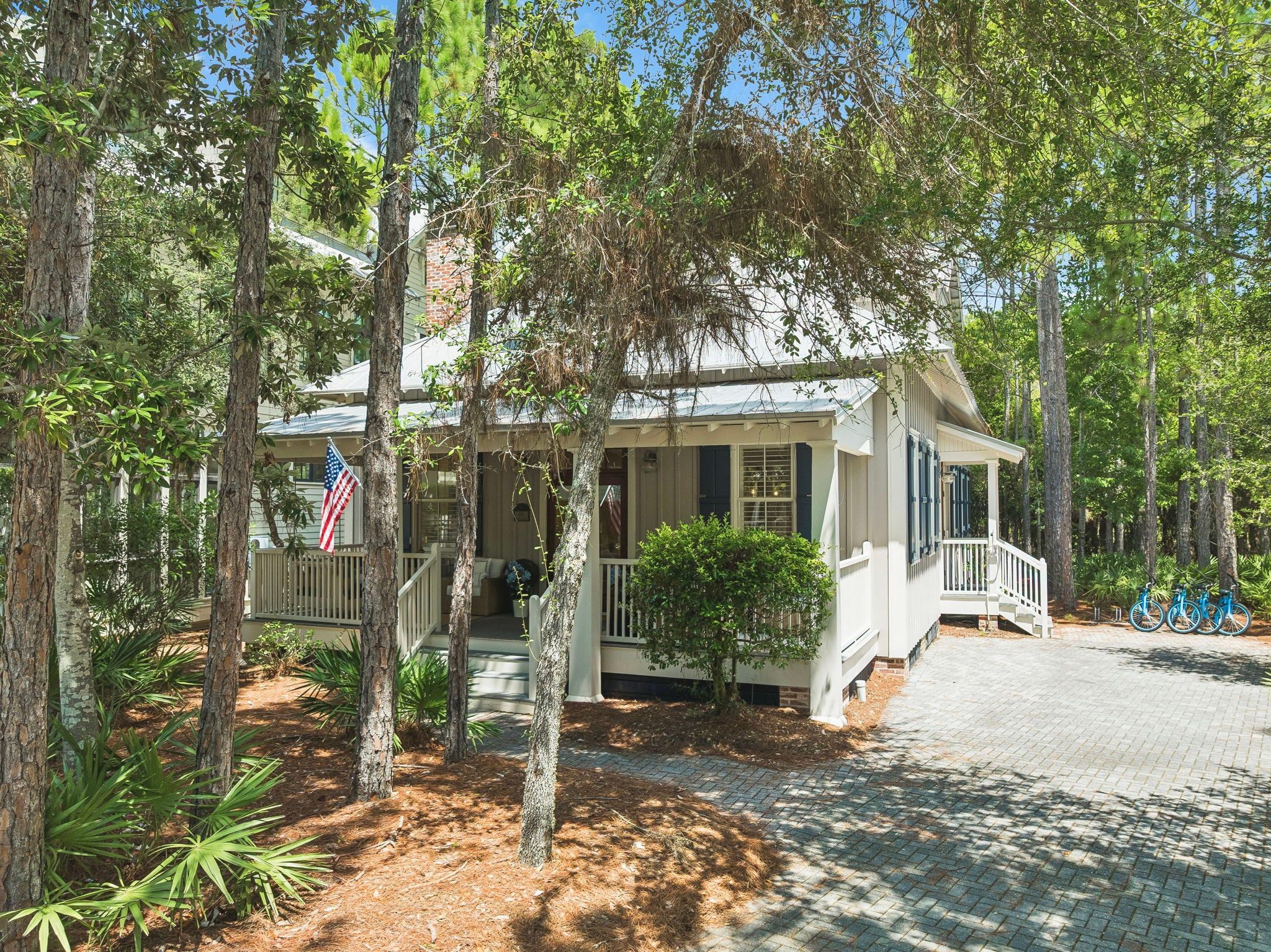 A two-story house with a porch, surrounded by trees.
