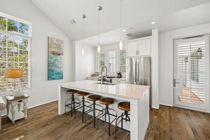 Eine moderne Küche mit einer zentralen Kochinsel, Barhocker und einem Edelstahl-Kühlschrank.