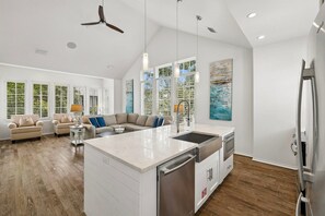 A spacious kitchen with a central island, modern appliances, and a dining area with a sofa. - Rosemary Beach! Private Saltwater Pool, Carriage House, & 4 Bikes! (Rosemary Beach)