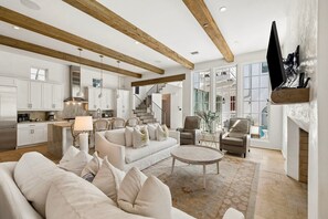 A spacious living room with a fireplace, a kitchen with modern appliances, and a staircase leading to an upper level. - Rosemary Beach! Private Saltwater Pool, Carriage House, & 4 Bikes! (Rosemary Beach)