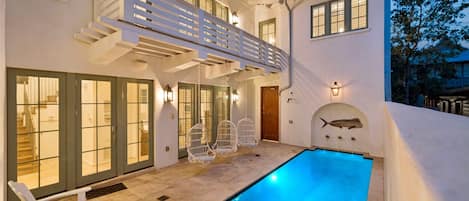 Een modern huis met een zwembad, terras en balkon.