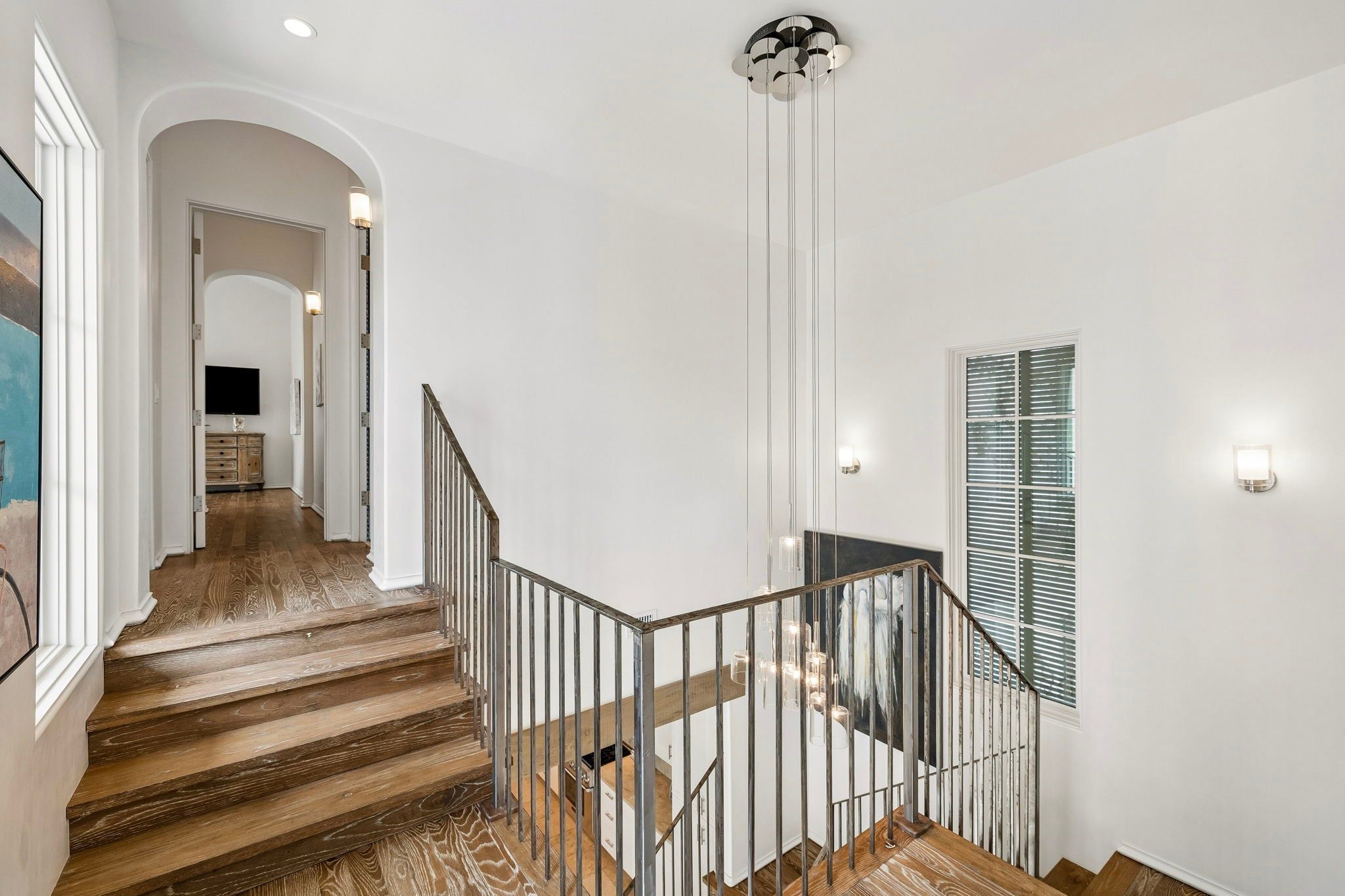 A staircase with wooden steps and metal railings, leading to a landing with a wall-mounted light fixture.