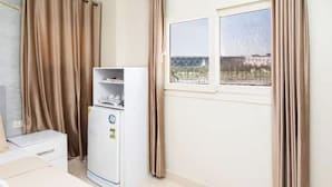 A room with a bed, a small table, a white cabinet, a window with curtains, and a refrigerator. - Gem View Inn (Giza Governorate,)
