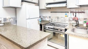 A kitchen with a granite countertop, stainless steel appliances, and white cabinetry. - Gem View Inn (Giza Governorate,)