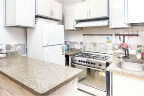 A kitchen with a granite countertop, stainless steel appliances, and white cabinetry. - Gem View Inn (Giza Governorate,)
