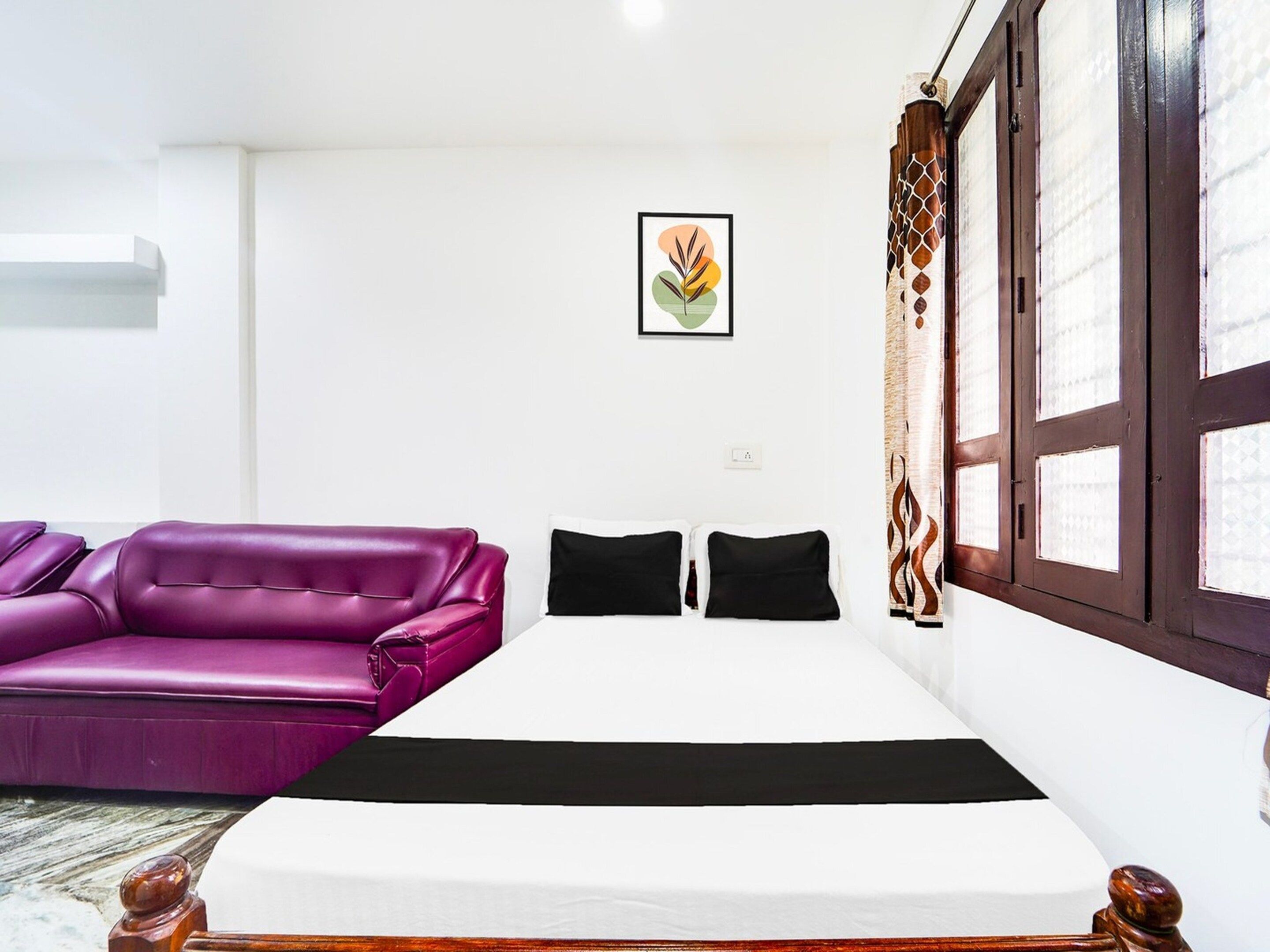 Une pièce avec un lit, un canapé violet et une fenêtre avec des rideaux.
