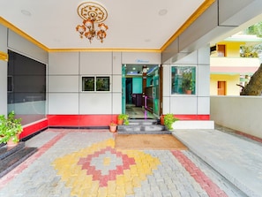 A hotel lobby with a patterned floor, a chandelier, and a 'Welcome' sign.