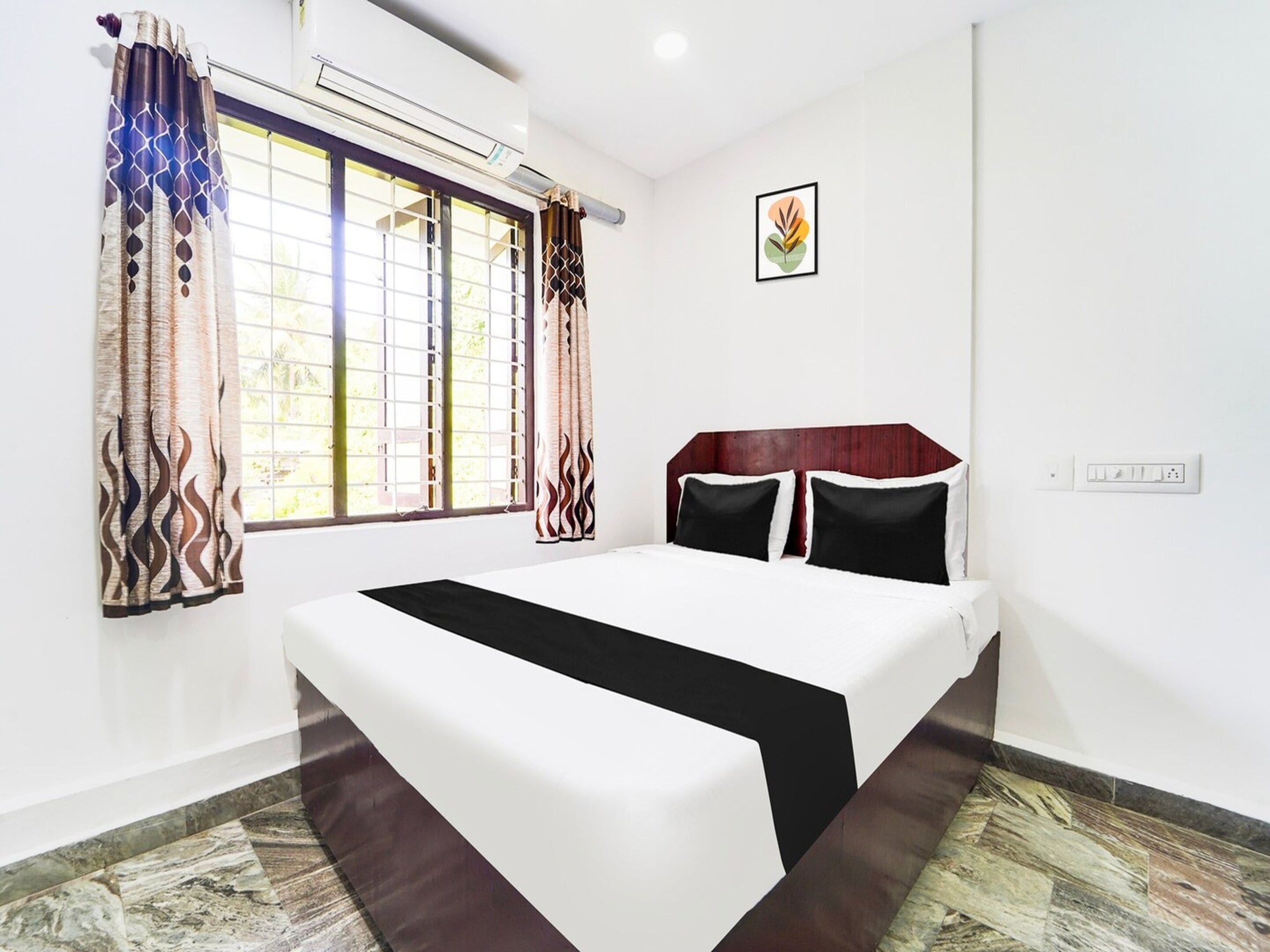 Une chambre à coucher comprenant un lit, des rideaux, un appareil de climatisation, un interrupteur fixé au mur et un tableau encadré.