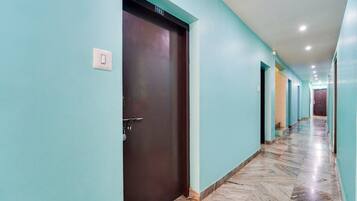 A hallway with teal walls, a marble floor, and a dark brown door marked with the number 103.