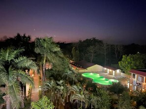 Un resort con piscina, rodeado de palmeras y un edificio de techo rojo.