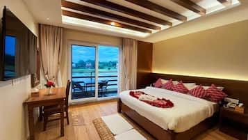 A hotel room with a bed, a desk, a chair, a TV, and a view of the outdoors.