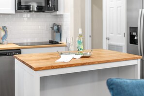 A kitchen with white cabinets, a wooden countertop, a bottle of liquor, and a glass. - Family‑Friendly 2BR Beach Home • Walk to Beach & Shops 🌴🏖️ (Cape Canaveral)