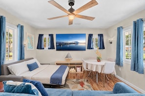 A bedroom with a bed, a desk, a chair, a dining table, and a ceiling fan. - Family‑Friendly 2BR Beach Home • Walk to Beach & Shops 🌴🏖️ (Cape Canaveral)