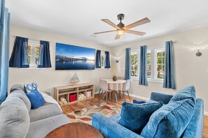 A living room with a sofa, a dining table, and a ceiling fan. - Family‑Friendly 2BR Beach Home • Walk to Beach & Shops 🌴🏖️ (Cape Canaveral)