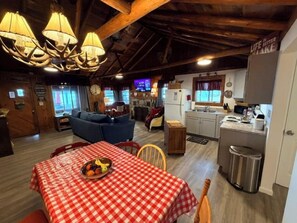 A cozy cabin interior with a dining area, kitchen, and living space. - New!  Chappy's Lakeside Cabin - Lakefront & Comfy!  Includes canoe and kayak! (Oscoda)