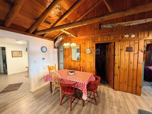 Ein Holzinterieur mit einem für vier Personen gedeckten Esstisch, einer Chandelüster und einer Holztür.