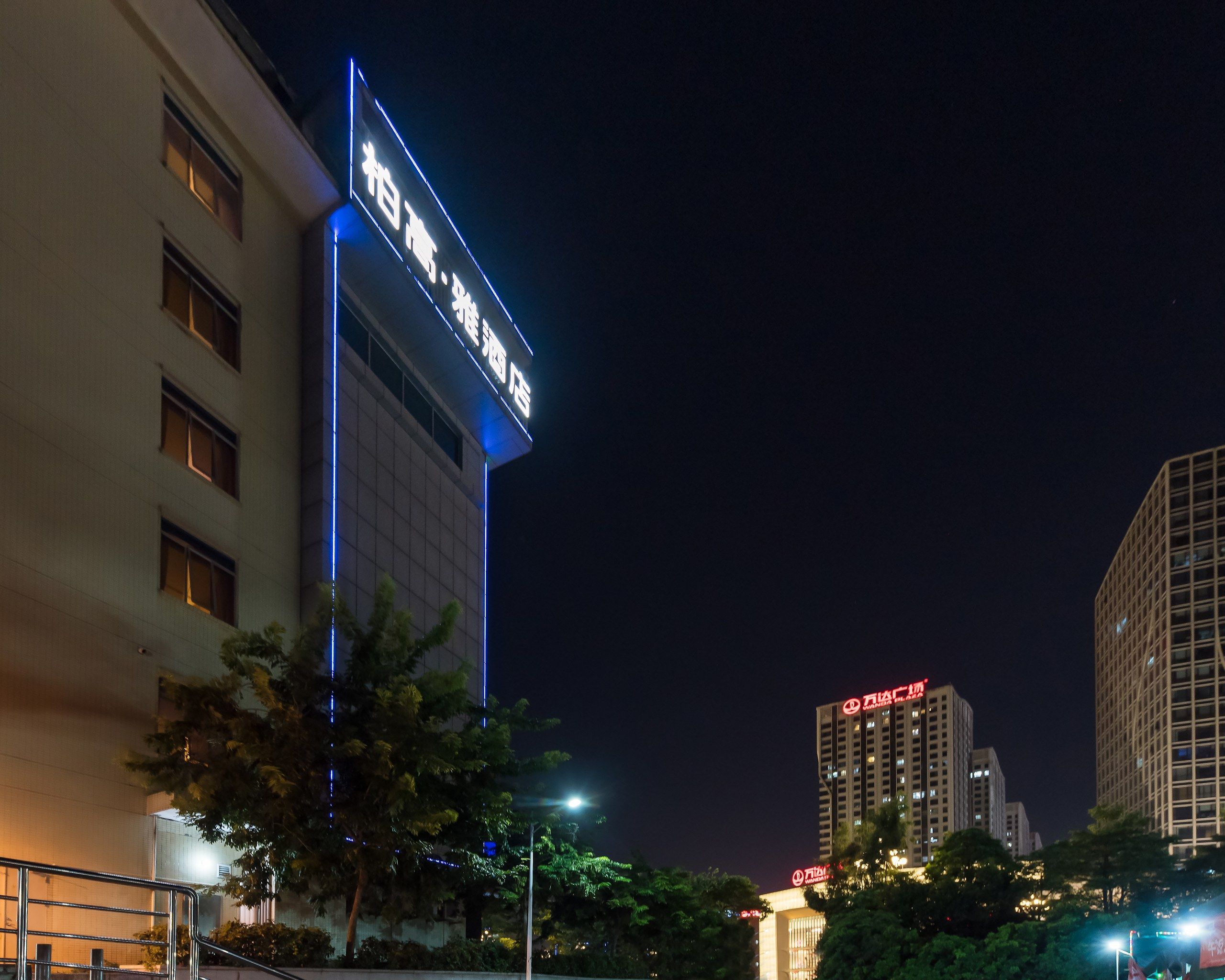 A building with illuminated signage, a clear sky, and surrounding trees.