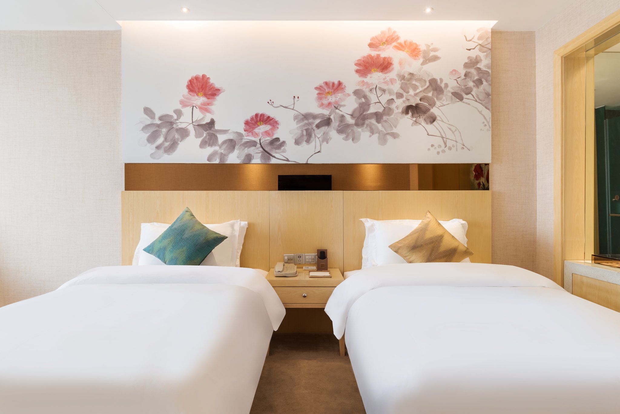 A hotel room with two beds, a nightstand, and a wall-mounted TV.