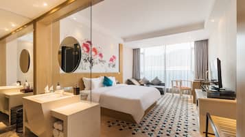 Ein modernes Hotelzimmer mit einem großen Bett, einer Sitzecke, einem Schreibtisch und einem Badezimmer.