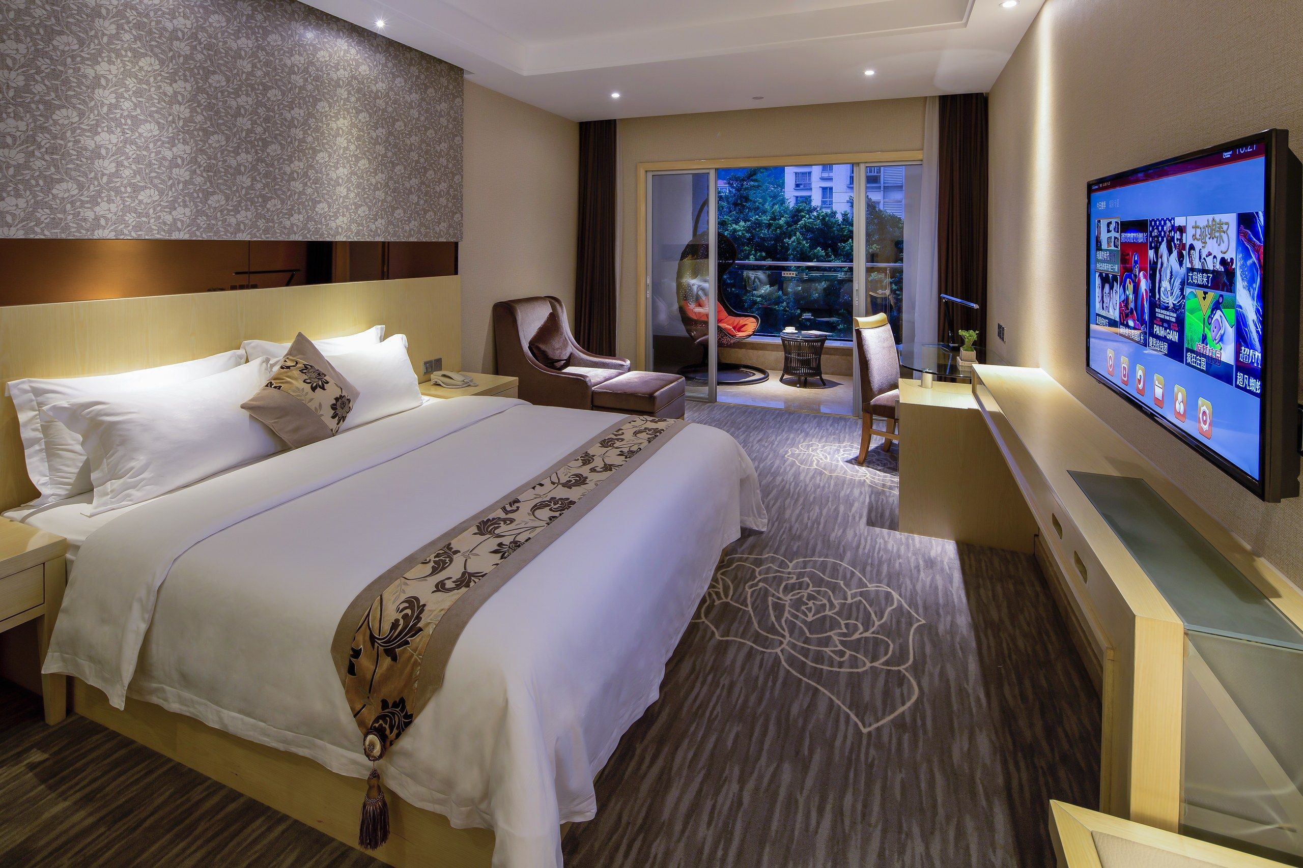 A hotel room with a large bed, a desk, a television, and a view of the outdoors.