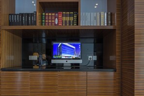 Una estantería de madera con libros y un televisor de pantalla plana.
