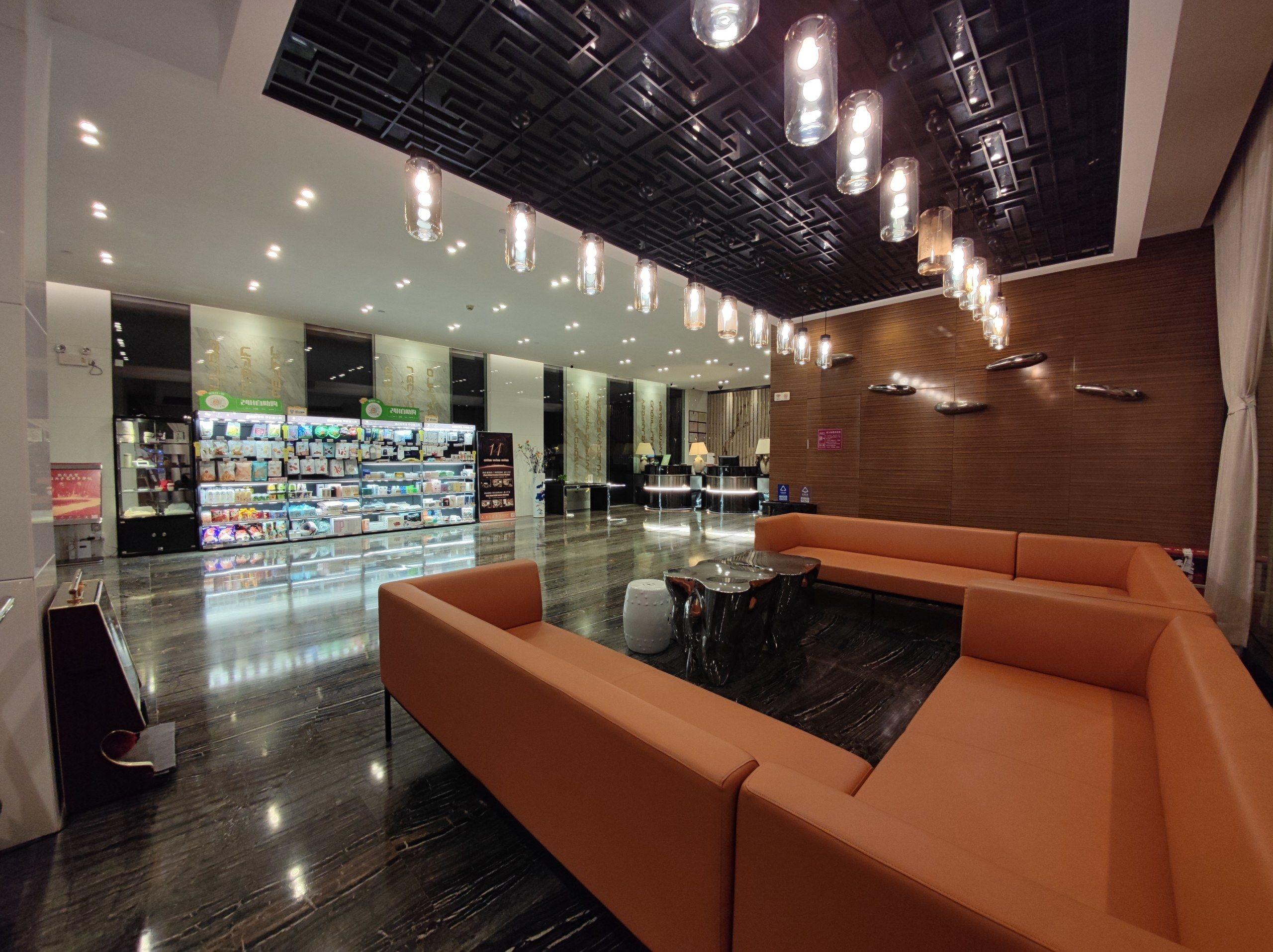 Een moderne lobby met een receptiebalie, een zithoek en automaten.