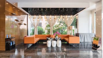 A modern lobby with a wooden accent wall, a sectional sofa, a coffee table, and a plant.