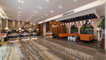 Um saguão de hotel com balcão de recepção, área de estar e vista para o exterior.